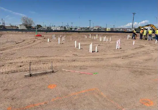 Vehicle tracks and markers in the dirt where construction is underway at Amadour Crossing.