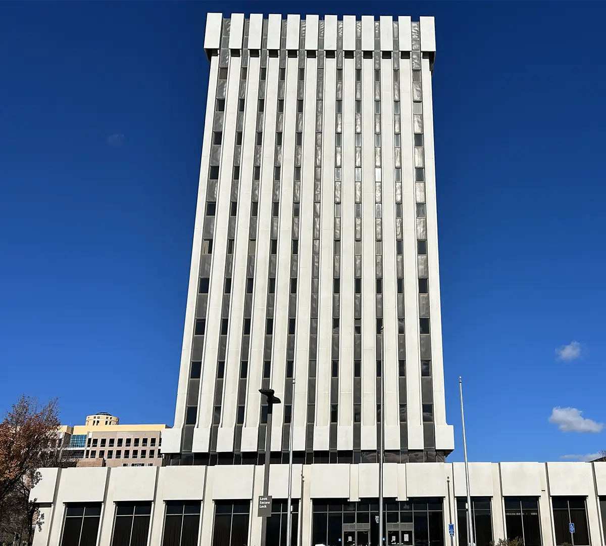 Wells Fargo building, a white tower with vertical lines of windows that give the impression of stretching upward above the larger base of the building.